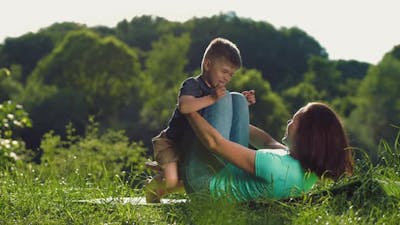 Mother with Little Son Doing Gymnastic Exercise Outdoors.