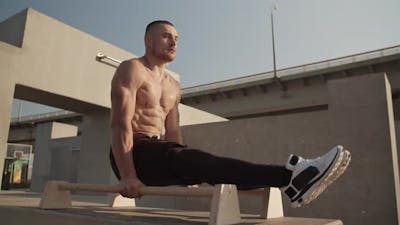 Muscular Sportsman Doing Gymnastic Exercise on Bars.