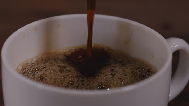 Filling a white cup of coffee .