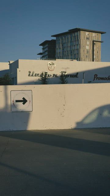 Young woman skating down a parking lot up to a fence.