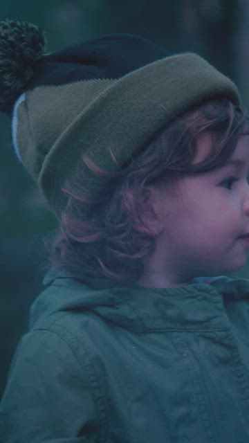 Little girl in nature with a marshmallow on a twig at a campfire.