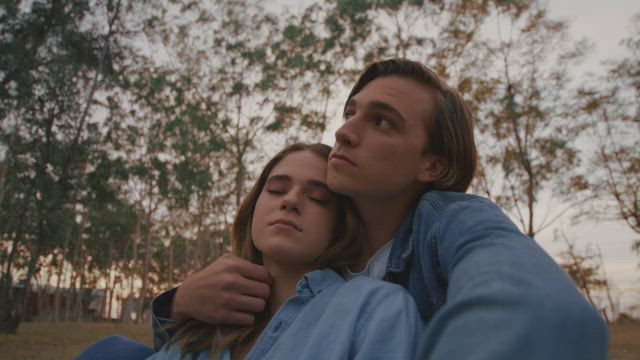 Romantic couple sitting on the grass in a forest.