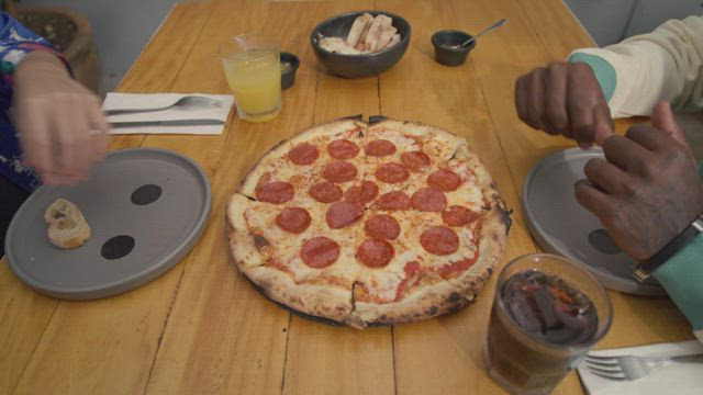 Man and woman taking a slice of pizza.