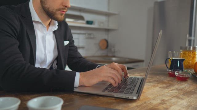 Man in a suit works from the kitchen.