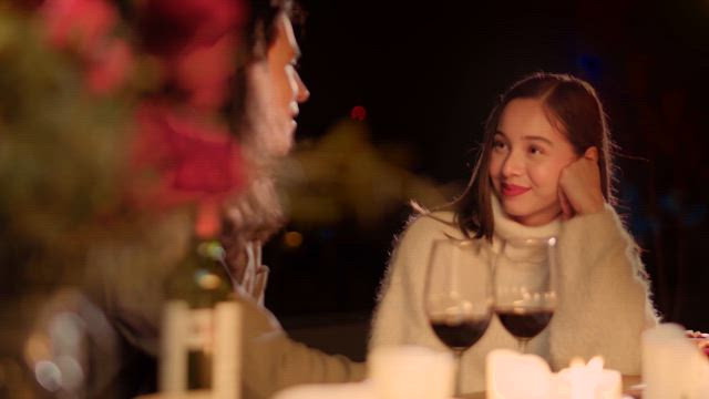 A young woman on a dater listening to the man's conversation amidst the candlelights.