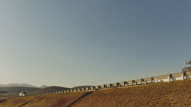 Trucks going in opposite directions encounter each other on the highway on a sunny day.