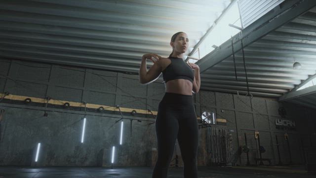 A young toned  woman wearing snugly sportsware doing squats at the gym.