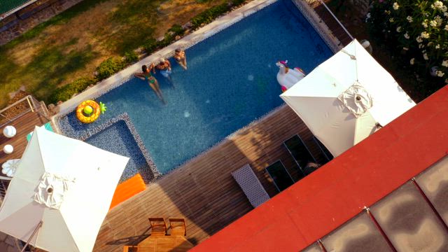 Three young carefree individuals enjoys a hot summer day chilling on the swimming pool.