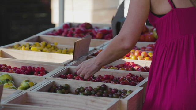 A woman choosing fruit at a market.